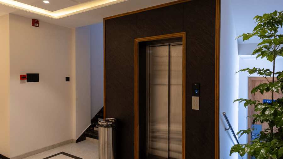The stylish lift lobby area with a checkered floor at Pravasa Stay Bapat Square, Indore.