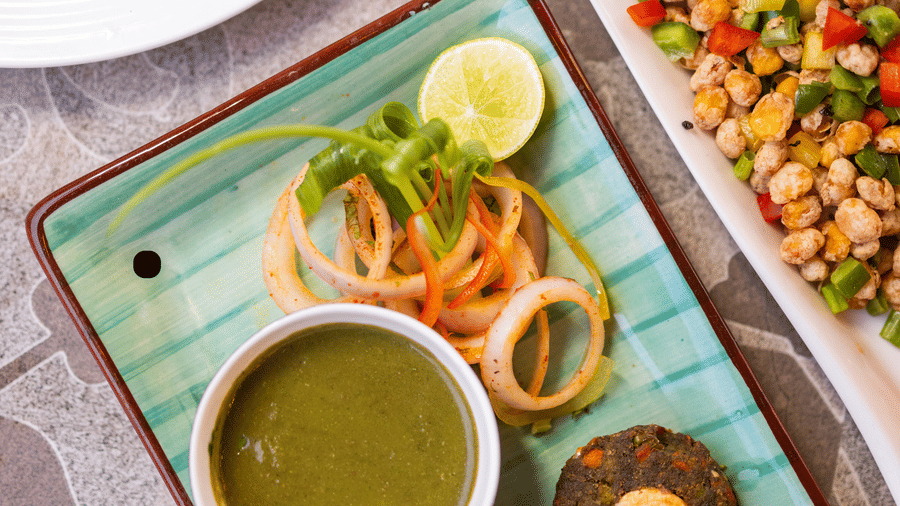 View of Indian dishes, including cutlets or kebabs, on a patterned table at Pravasa Stay Luv Kush, Indore.