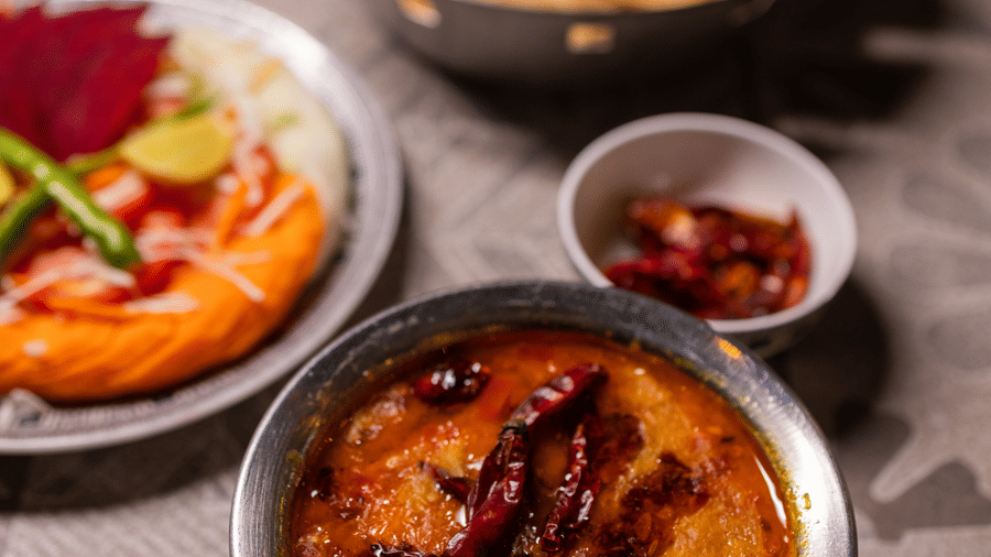 View of a flatbread dish, possibly a main course, with several small side dishes at Pravasa Stay Luv Kush, Indore.