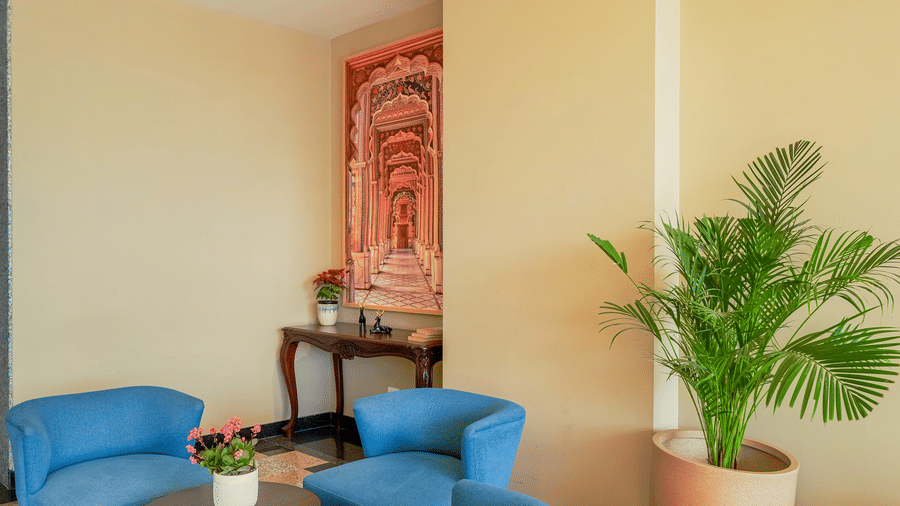 The reception at Urban Suites by BluSalzz, Jaipur, with a tiled floor, featuring seating arrangements, low tables, and a plant.