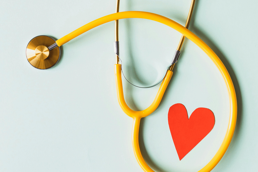 An yellow stethoscope looping a red paper art of a heart