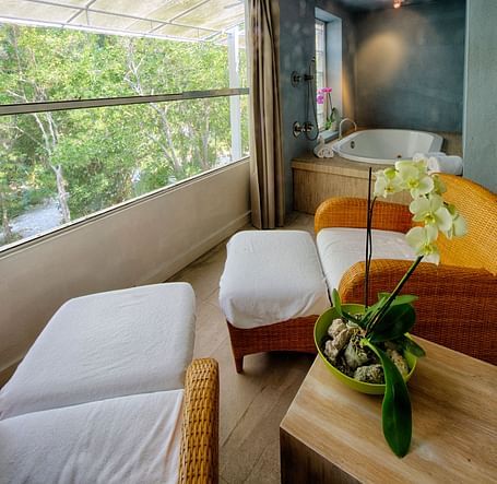 Seating area at Casa Morada with two white chairs, a round table, and a view of greenery through a large window.