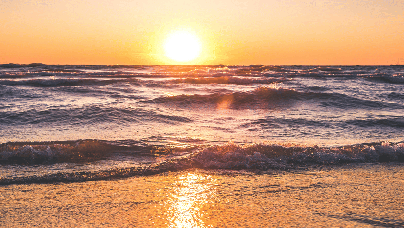 image of a beautiful sunset at a beach side with sun rays reflecting in the water