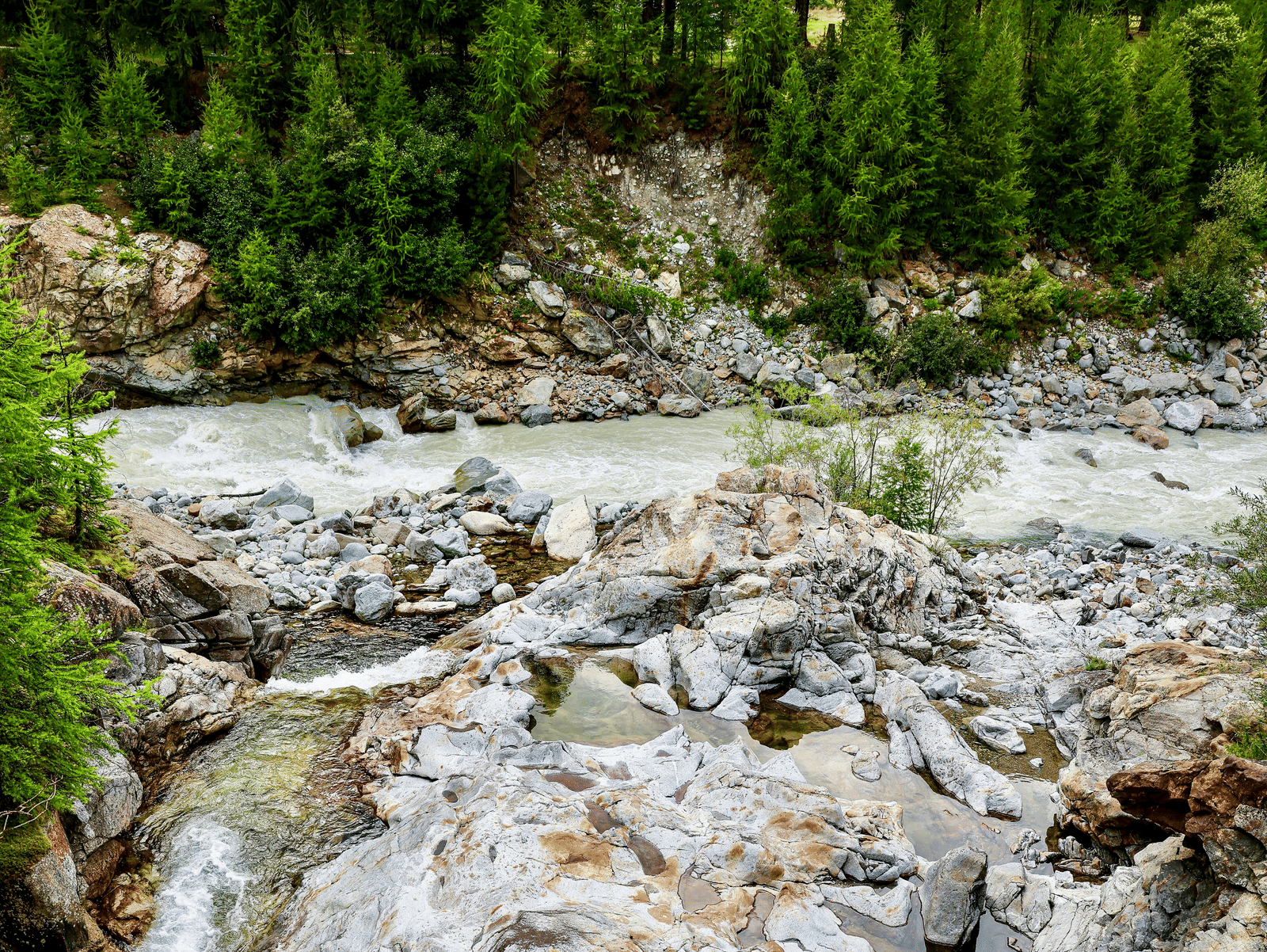 An overview of a stream on limestone rocks with greenery in the background.