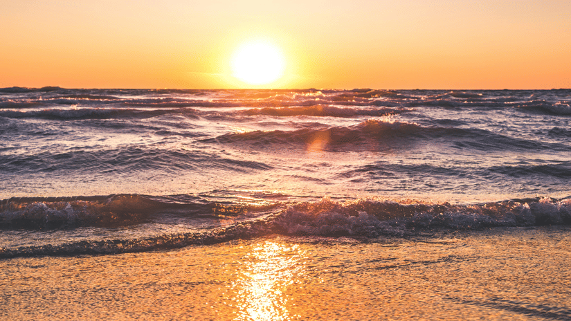 image of a beautiful sunset at a beach side with sun rays reflecting in the water
