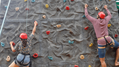 A person climbing a colourful artificial rock wall at Black Thunder Water Theme Park.