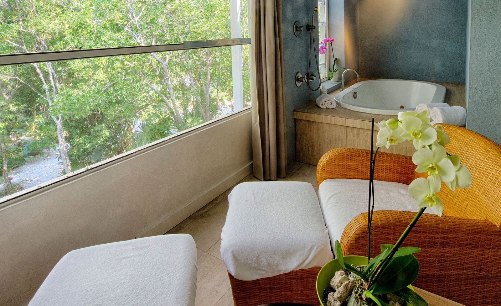 Seating area at Casa Morada with two white chairs, a round table, and a view of greenery through a large window.