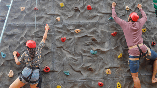 A person climbing a colourful artificial rock wall at Black Thunder Water Theme Park, one of the most exciting adventure places in Coimbatore.
