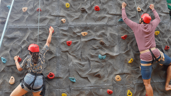 A person climbing a colourful artificial rock wall at Black Thunder Water Theme Park, one of the most exciting adventure places in Coimbatore.