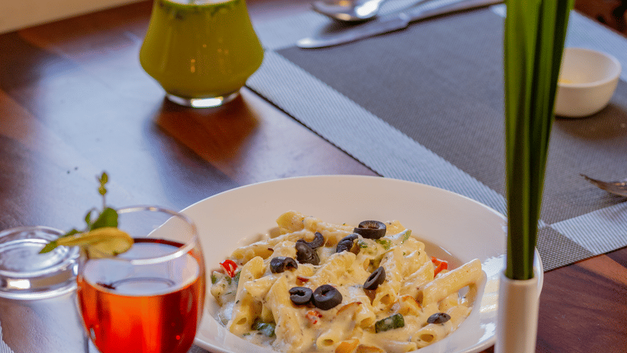 A salad plate and colorful beverages placed on a wooden table by a window at Estherea Bagh, Ranthambore.