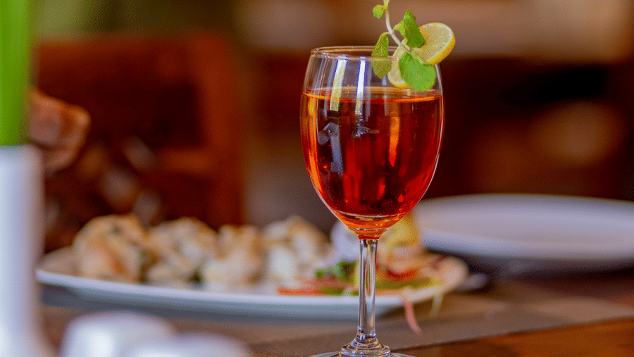 A close-up of a beverage and appetizers served on a wooden dining table at Estherea Bagh, Ranthambore.