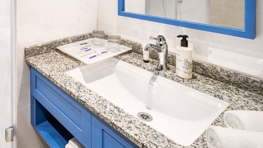 An image showing a bathroom featuring a distinct shower cubicle, a mirror, a sink, and a wall-installed bathroom phone - MJ Sarovar Portico, Haridwar