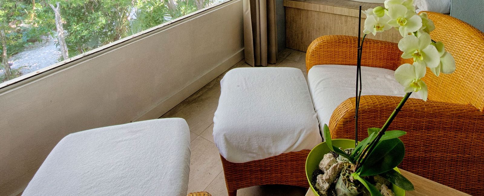 Seating area at Casa Morada with two white chairs, a round table, and a view of greenery through a large window.