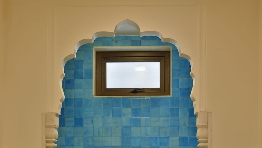 A bathroom at Royal Heritage Haveli with a unique blue tiled shower area and light-coloured walls.