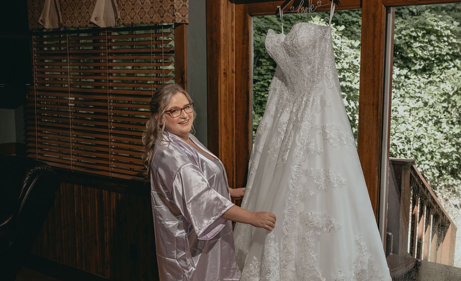 Bride holding her wedding gown which is hanged at the entrance of the cottage of the Historic Tapoco Lodge.