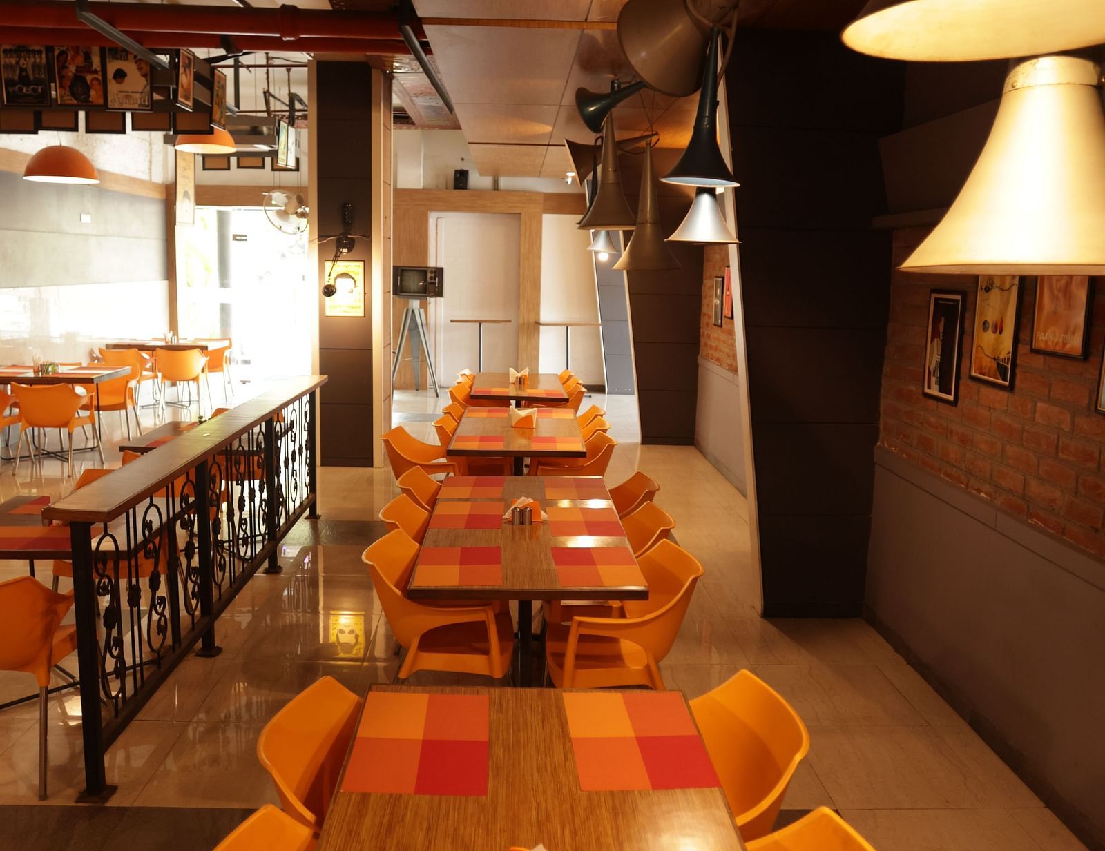 a long wooden dining area with orange coloured cushioned chairs arranged around it - Max Hotel, Jabalpur