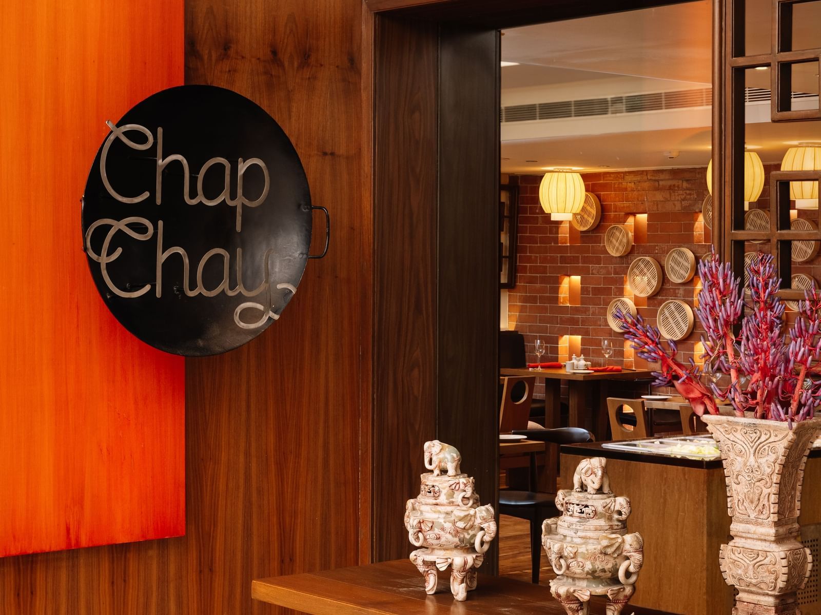 A vibrant and elegant restaurant entrance featuring rich colours, a board with 'Chap Chay' written on it , and a table with showpieces at The Raintree, St. Mary's Road.