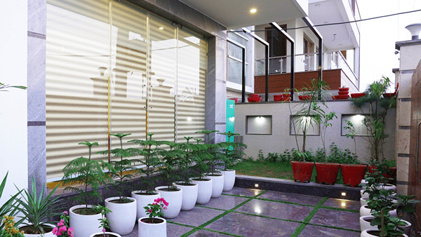 Exterior corridor of Lime Tree Hotel, Pulkit featuring potted plants and glass railings.
