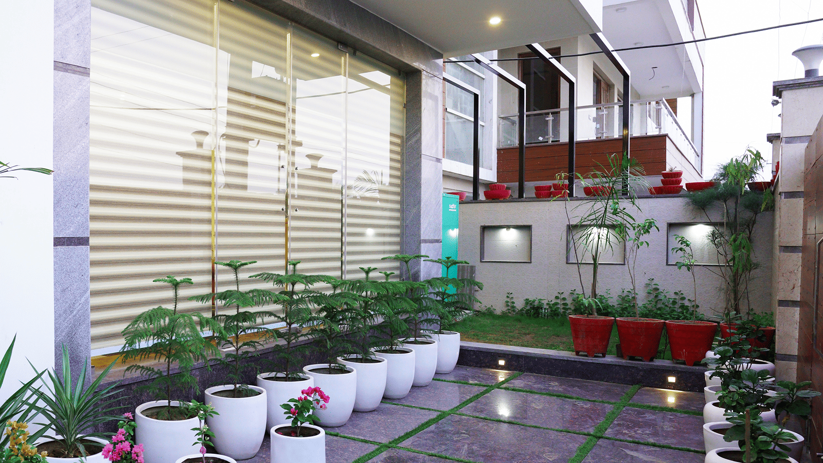 Exterior corridor of Lime Tree Hotel, Pulkit featuring potted plants and glass railings.