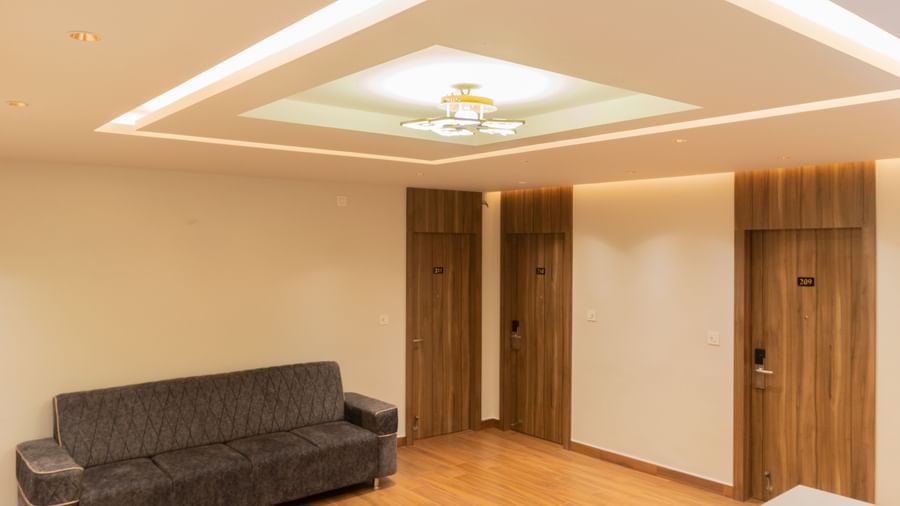 Modern lounge with a sofa, wooden flooring, and stylish ceiling lights at Beestay Hotels, Rajahmundry.