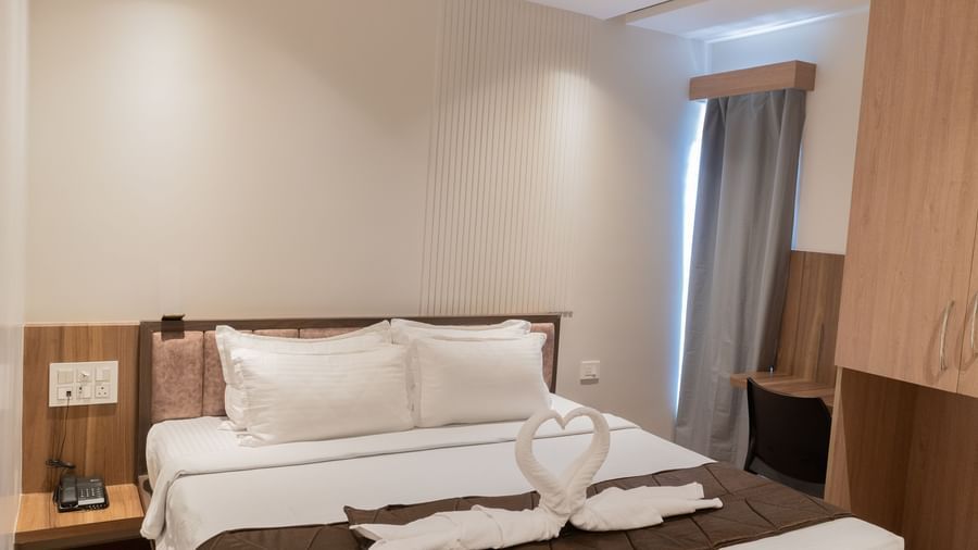 Spacious bed with towel swan decoration on top at Beestay Hotels, Rajahmundry.