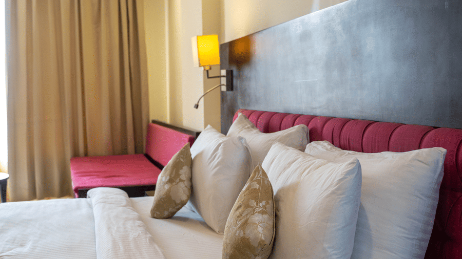 A luxurious hotel bed with plush pillows against a sleek wooden headboard for a relaxing stay in Udaipur at Hotel Udai Median, Sukhadia Circle