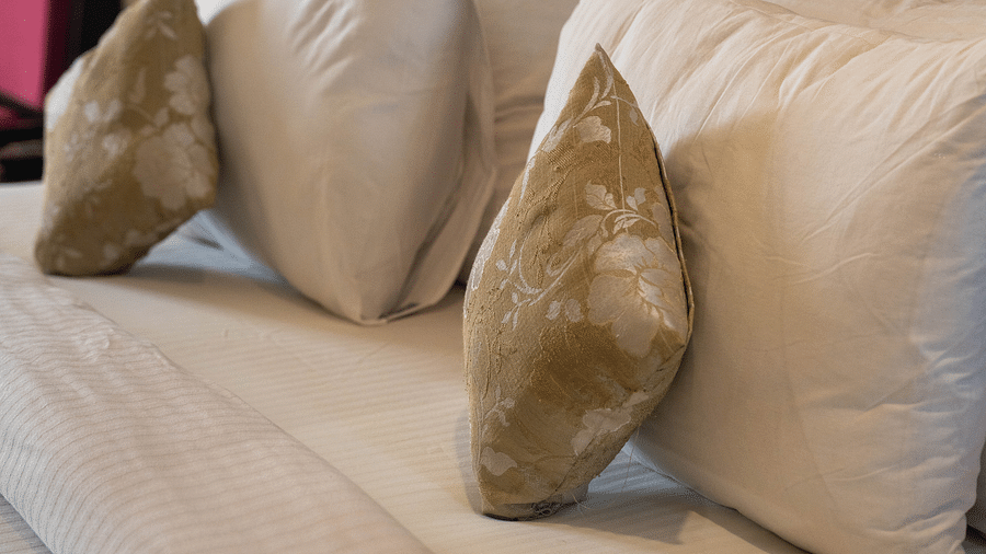 A luxurious hotel bed with plush pillows against a sleek wooden headboard - Hotel Udai Median, Udaipur.