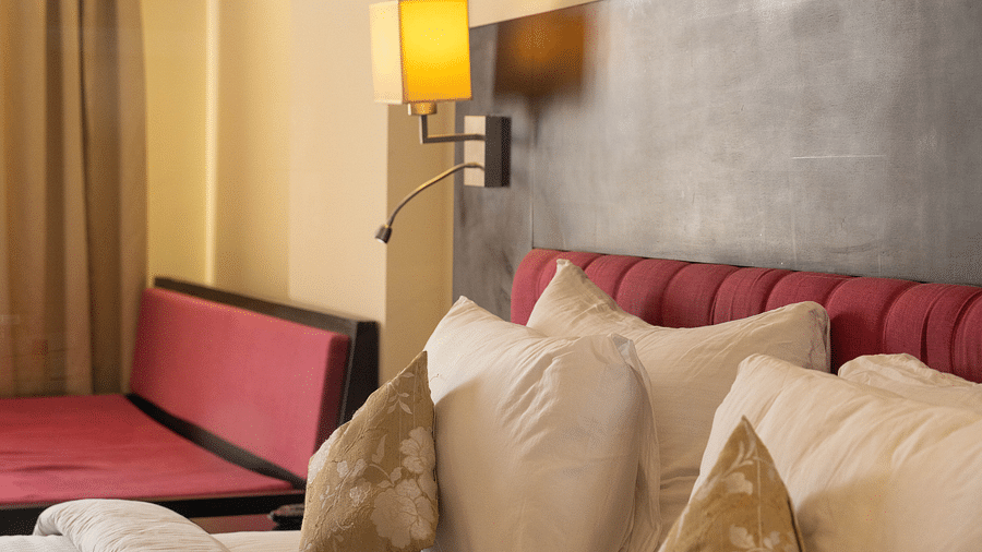 A hotel bed with plush pillows, a bedside lamp, and elegant golden accents - Hotel Udai Median, Udaipur.