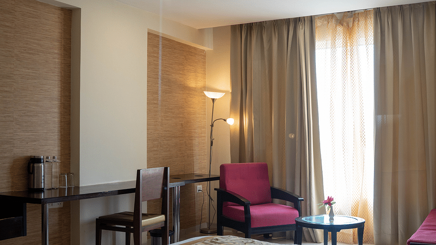 A cosy hotel room featuring a neatly made bed, an armchair, and soft lighting - Hotel Udai Median, Udaipur.