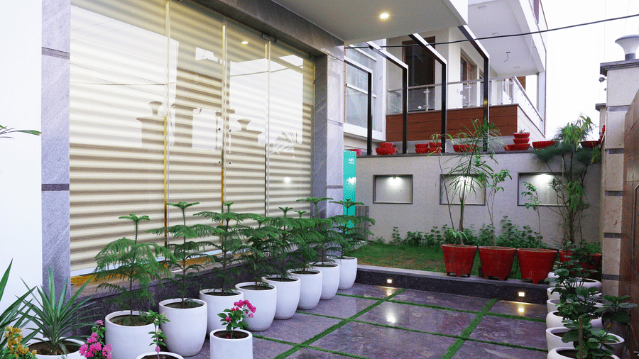 Exterior corridor of Lime Tree Hotel, Pulkit featuring potted plants and glass railings.