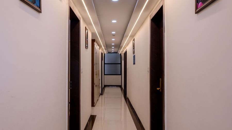 Narrow corridor with wall lights and framed pictures at Pravasa Stay Dewas Naka, Indore.