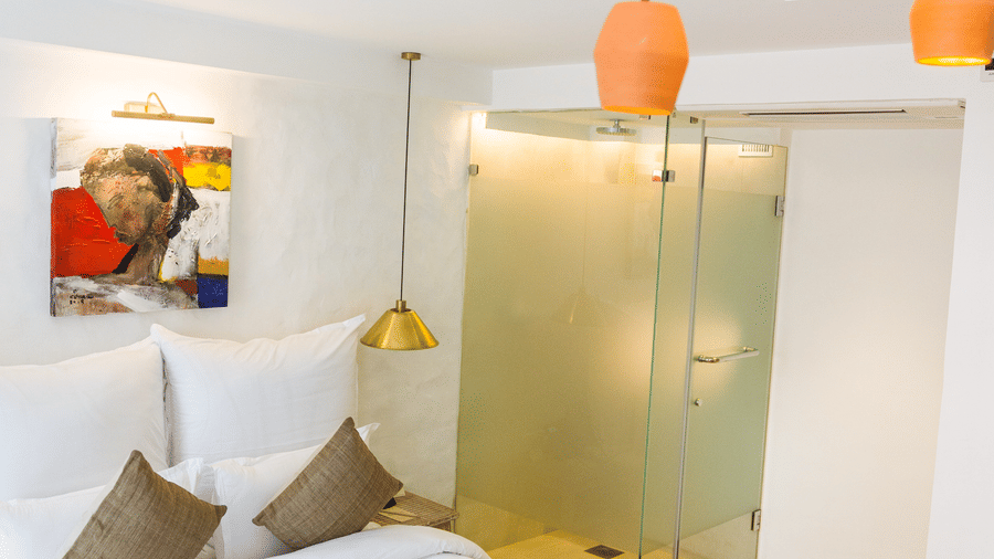 Deluxe loft room with a bed, bed side tables, and chandelier hanging - The Nanee