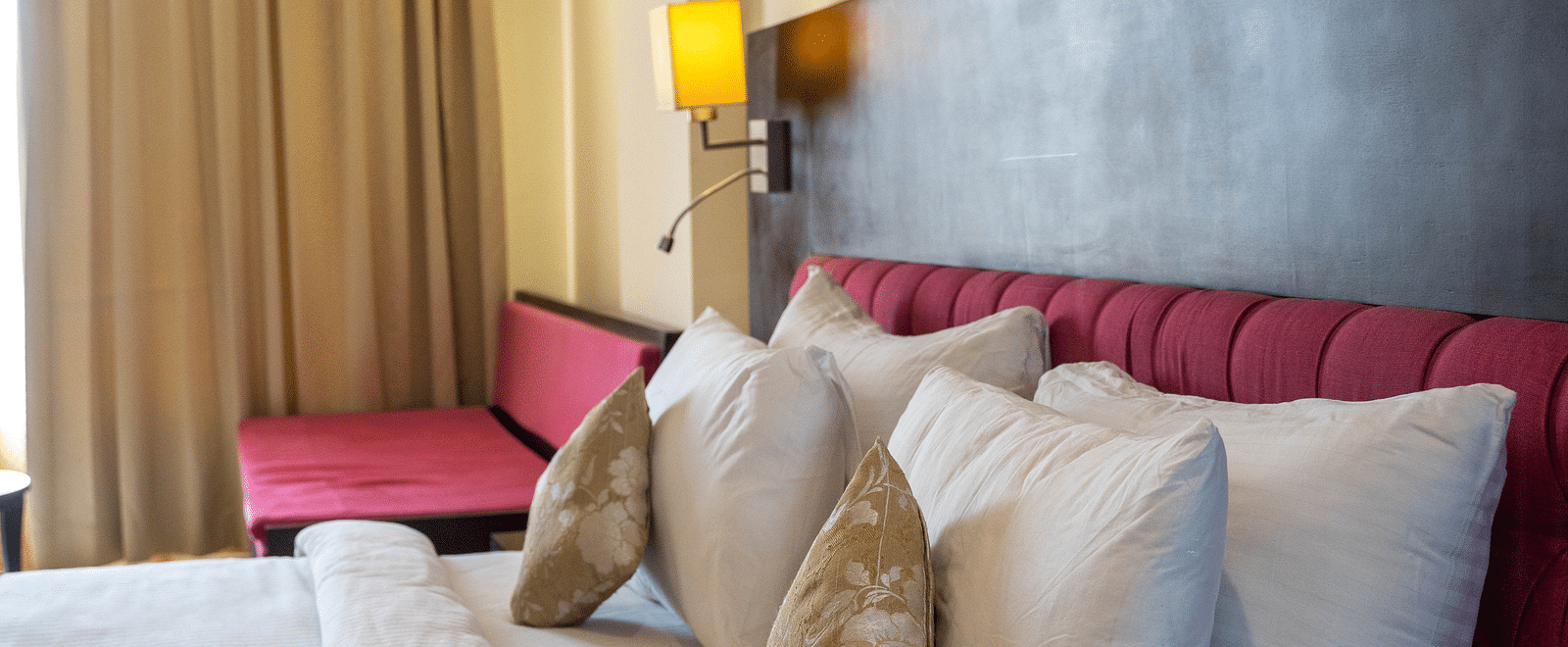 A luxurious hotel bed with plush pillows against a sleek wooden headboard - Hotel Udai Median, Udaipur.