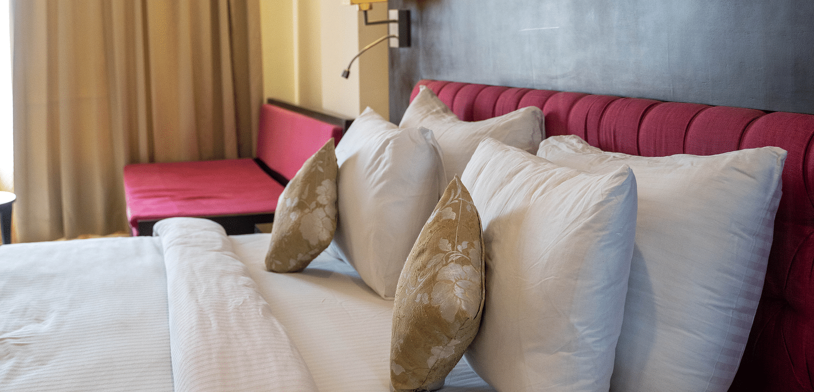 A luxurious hotel bed with plush pillows against a sleek wooden headboard - Hotel Udai Median, Udaipur.