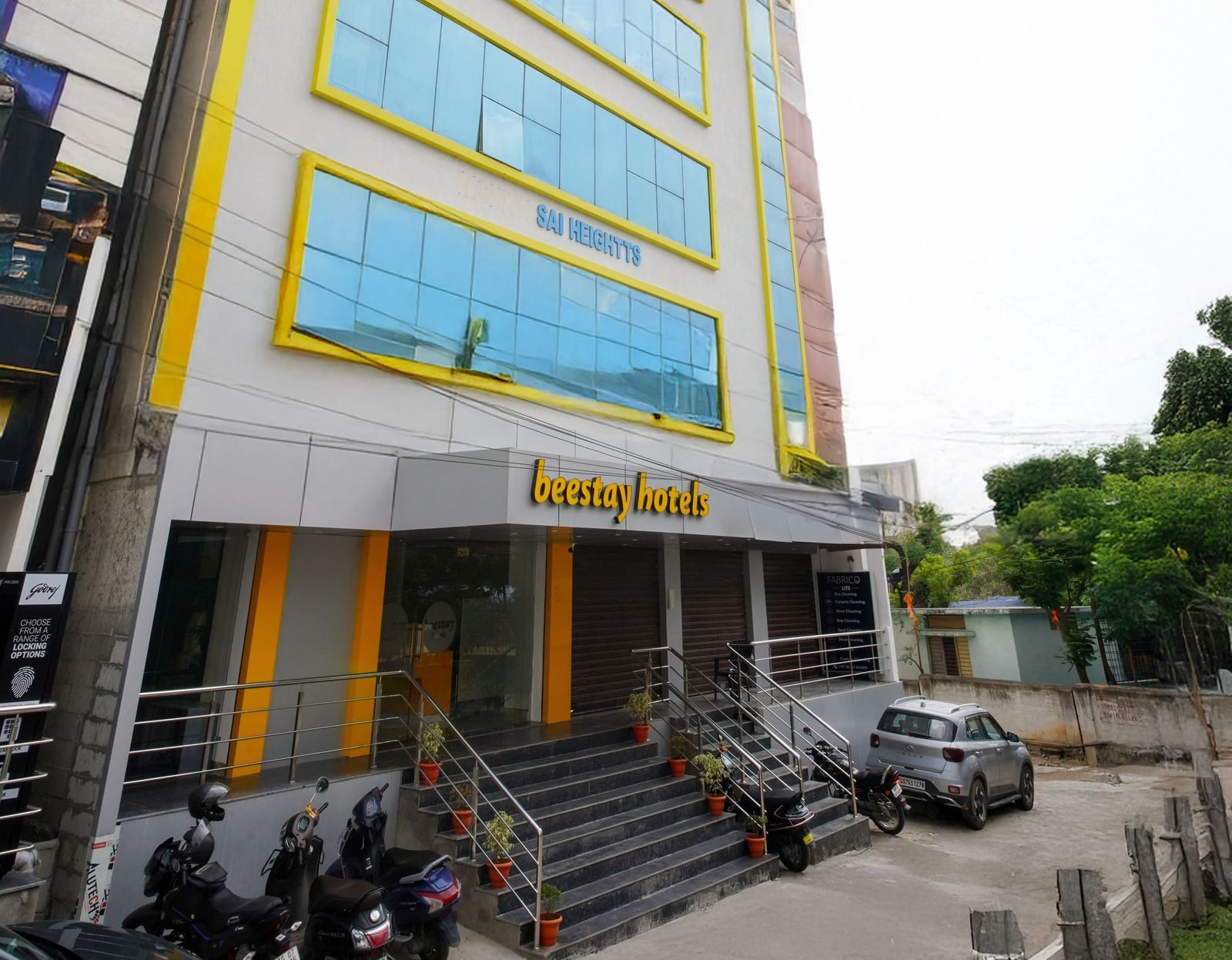 Side view of a multi-story building with blue-tinted windows and Beestays Hotels written on the facade - Beestay Hotels Financial District, Hyderabad 