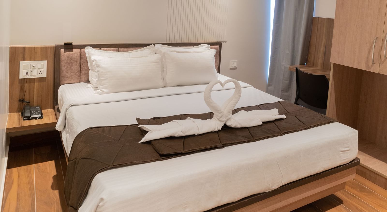 Spacious bed with towel swan decoration on top at Beestay Hotels, Rajahmundry.