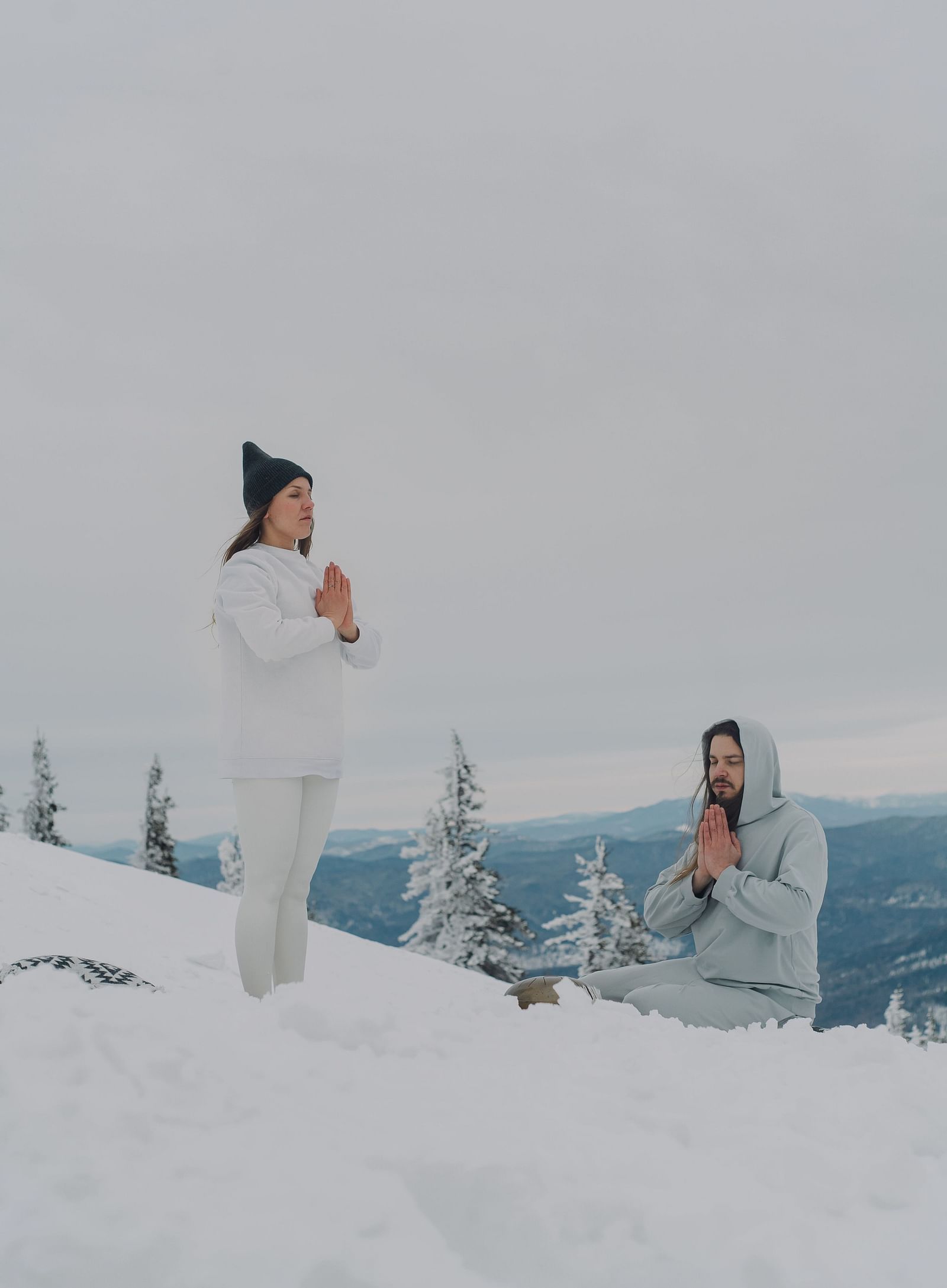 a couple performing yoga asanas together on a snow covered mountain
