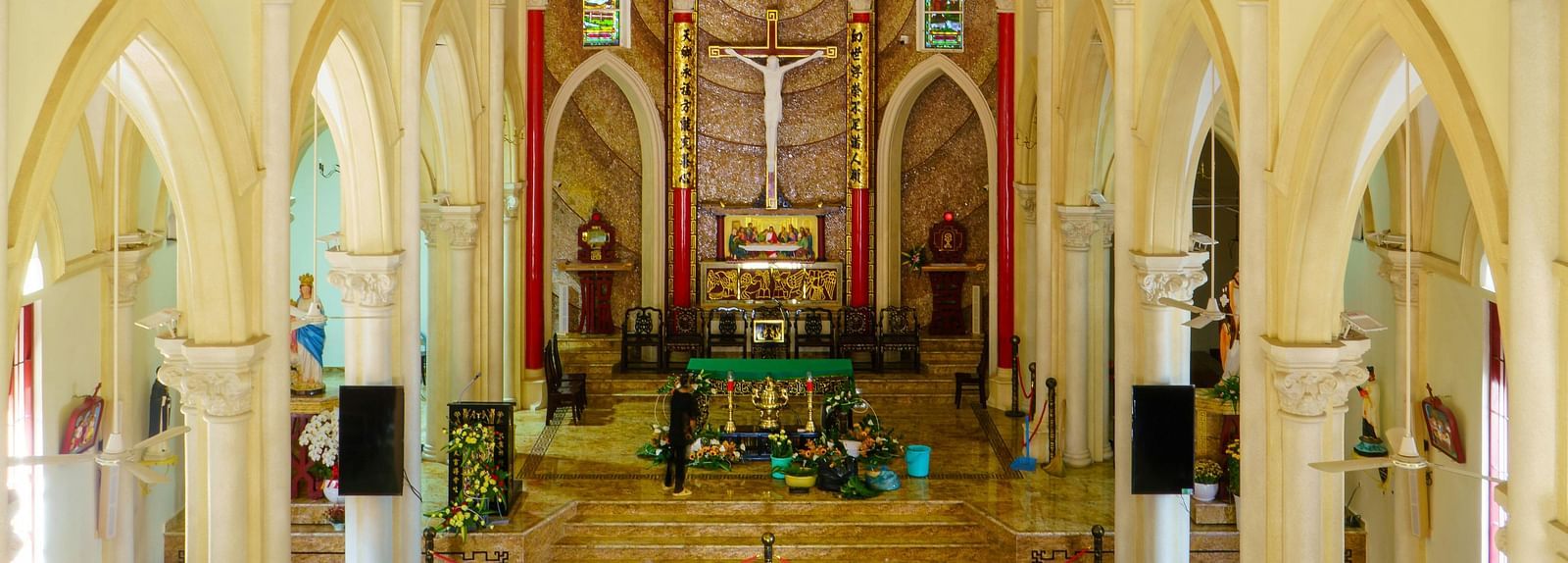 interior of a church with antique interior styling, carved roof, a chandelier with chairs beneath and the service addressing platform in the  far end