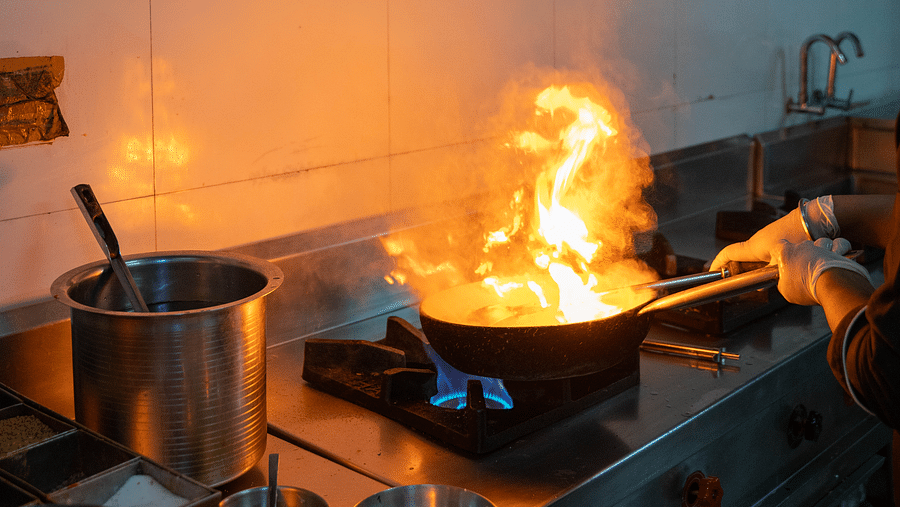 A chef cooking over a high flame in a professional kitchen - Hotel Udai Median, Udaipur.