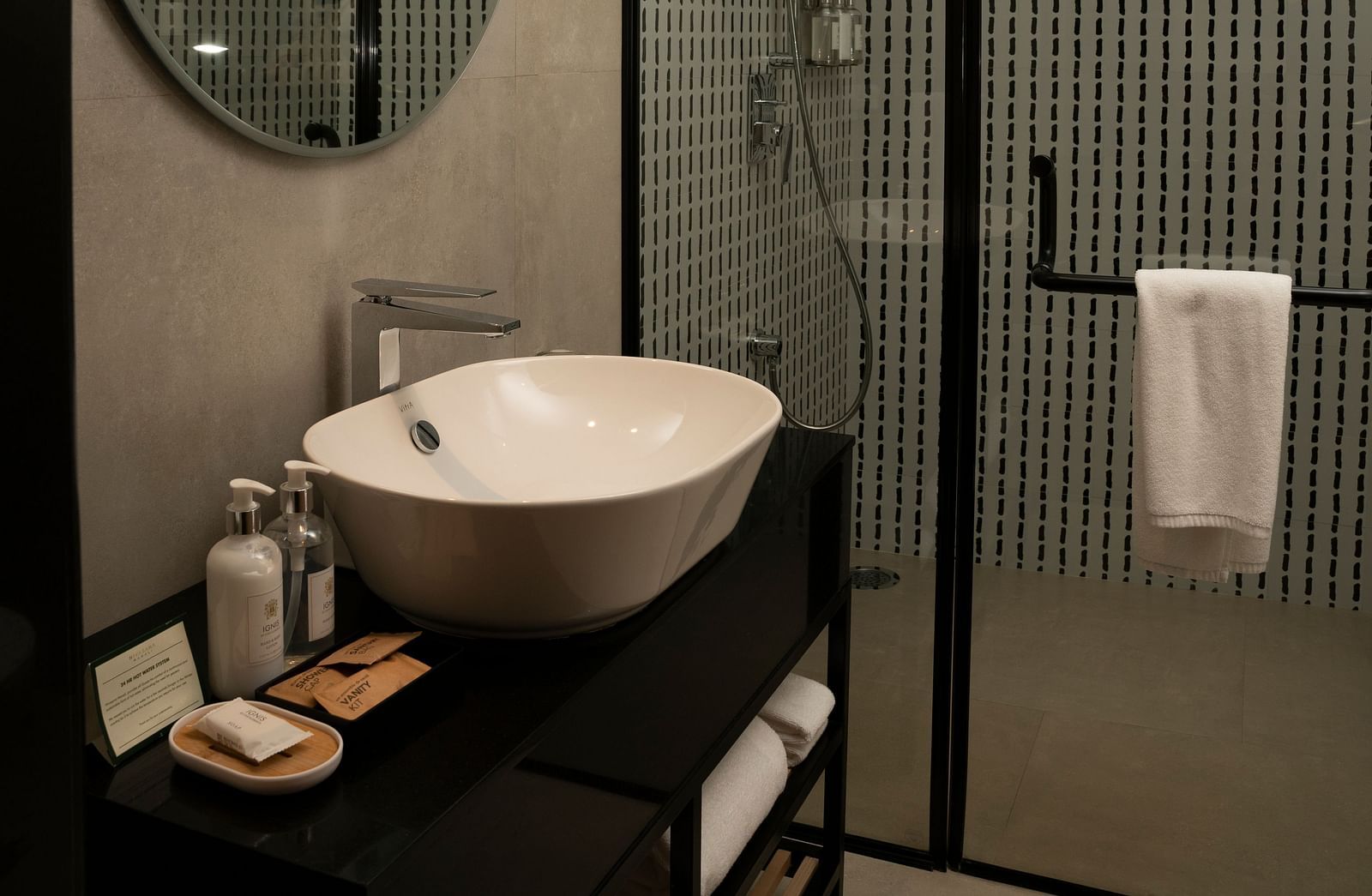 Compact bathroom with an oval mirror and glass shower at Nivasana Manali.