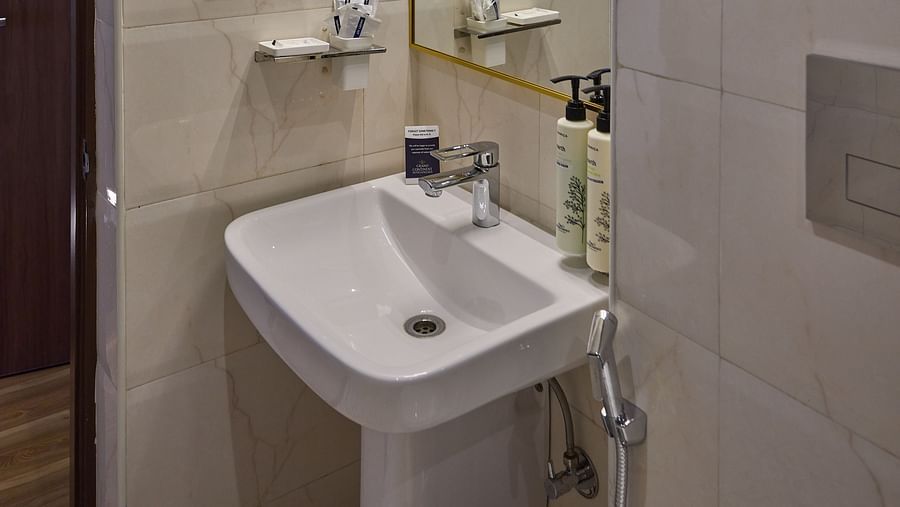 A sink positioned below a wall-mounted mirror in our hotel restroom - Grand Continent, Brookefield