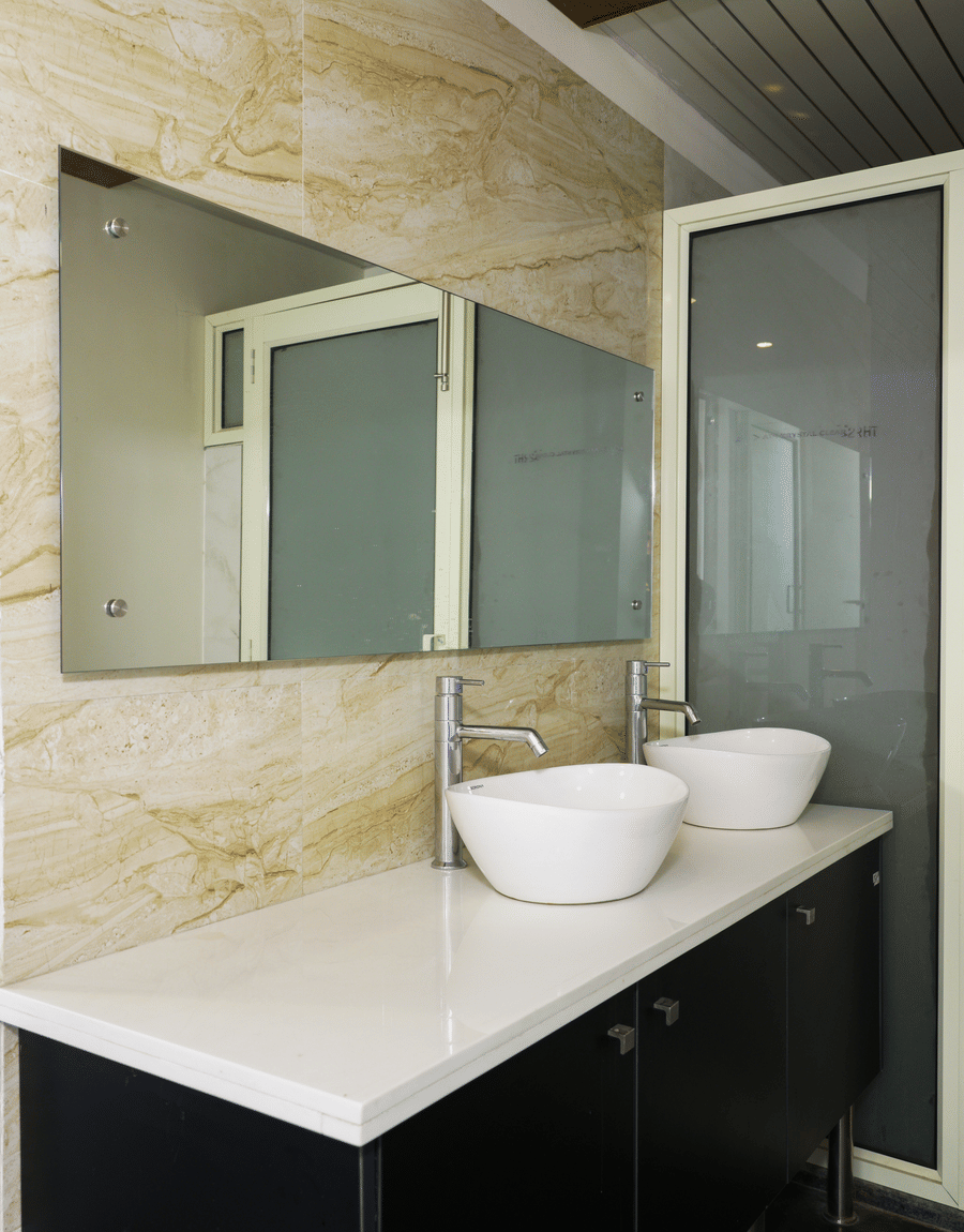 Twin washbasins on a white vanity with mirrors in the Deluxe Room bathroom at Lime Tree Hotel, Pulkit, Gurgaon