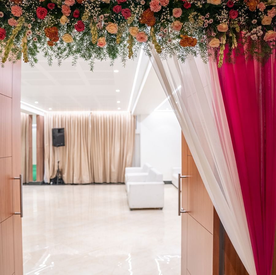 A decorated entrance to a wedding venue with drapes and floral arrangements.