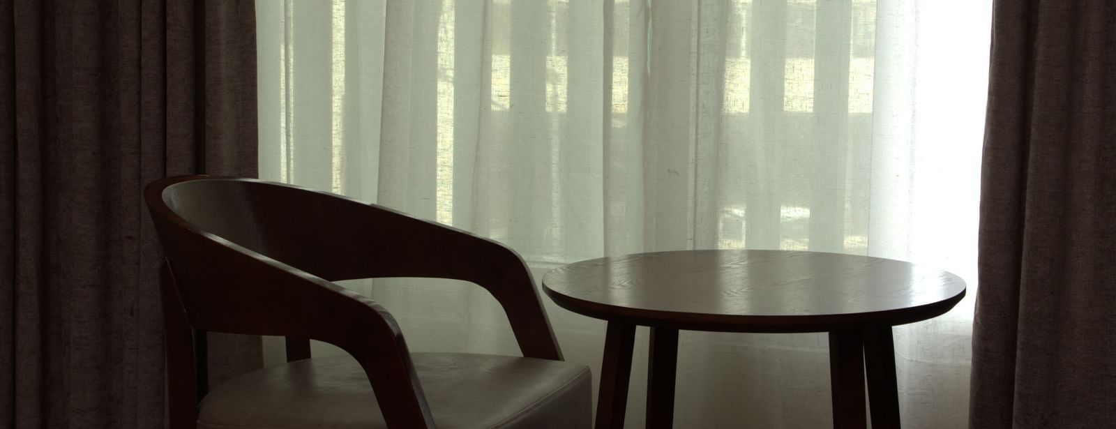A seating area with a single seater nearby a glass window at The Hamuse Hotel, Kodaikanal