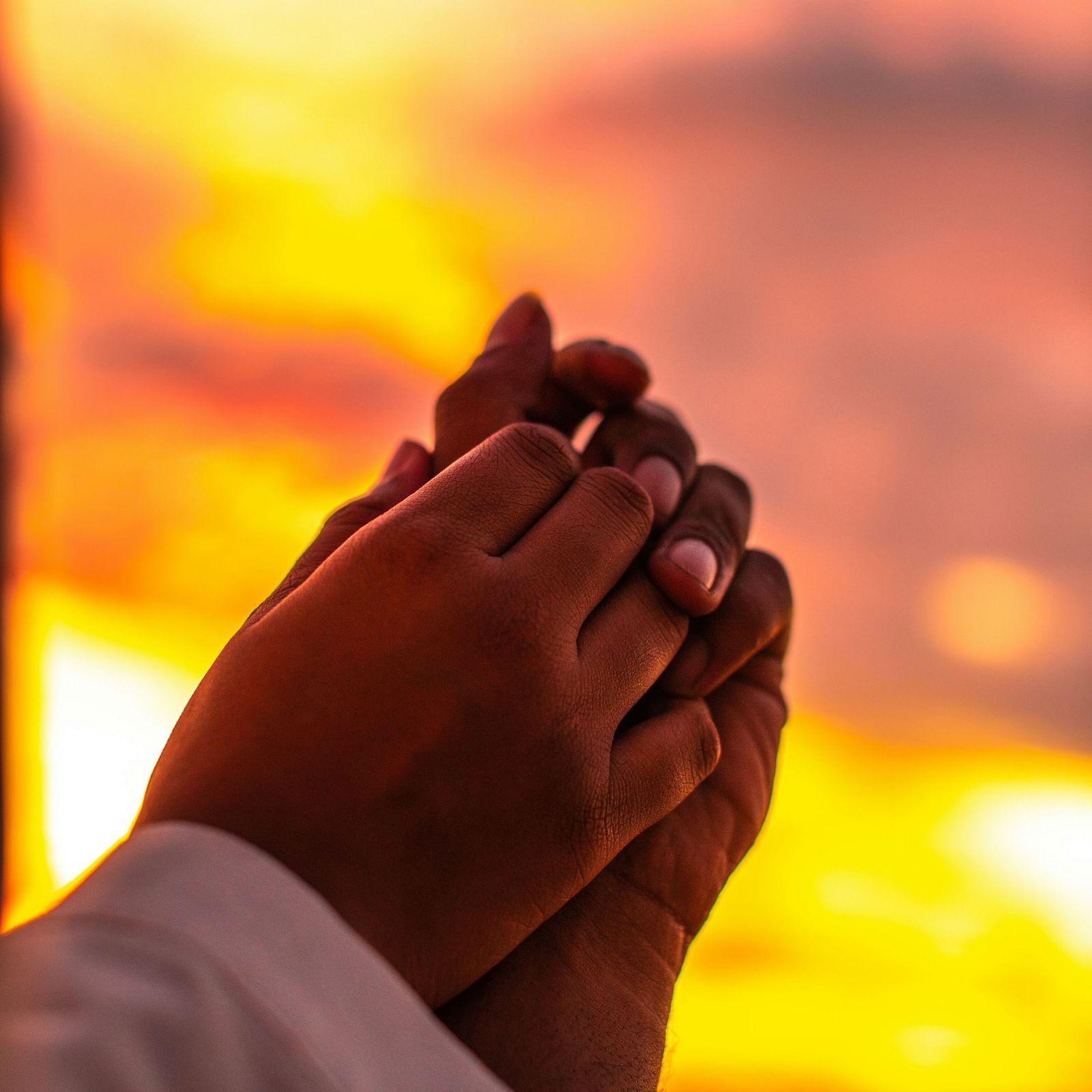 A couple holding hands with a serene sunset in the background