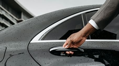 A concierge opening the door to a black car