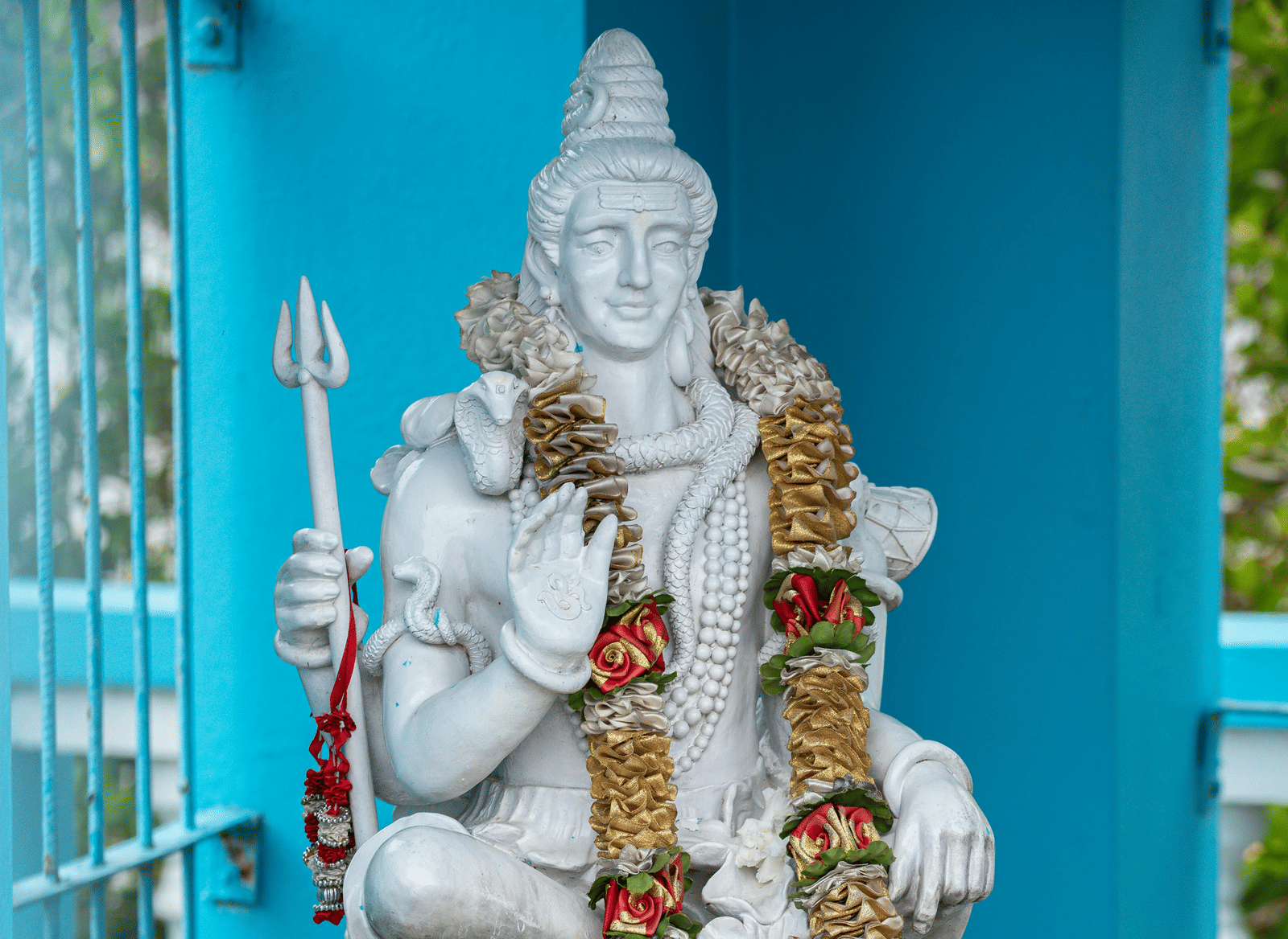 A statue of Lord Shiva made of white marble adorned with a flower garland around its neck.