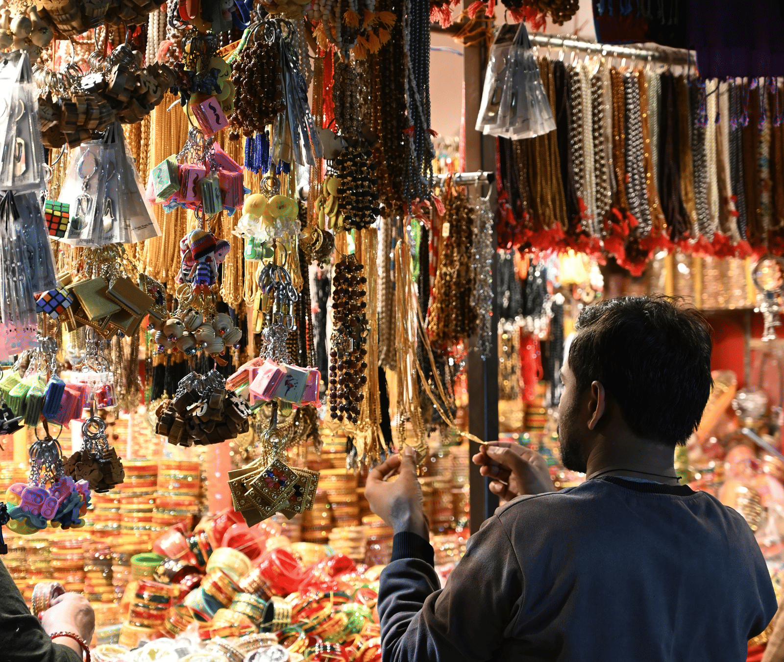 A person looks at colourful bracelets hanging at a market.