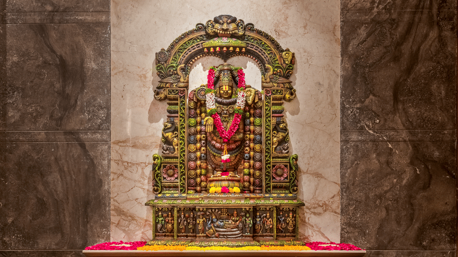 An intricate Lord Balaji statue set against a marble wall, with a colourful floral rangoli and a traditional oil lamp in the foreground - Skkylight Lords Inn, Nanded