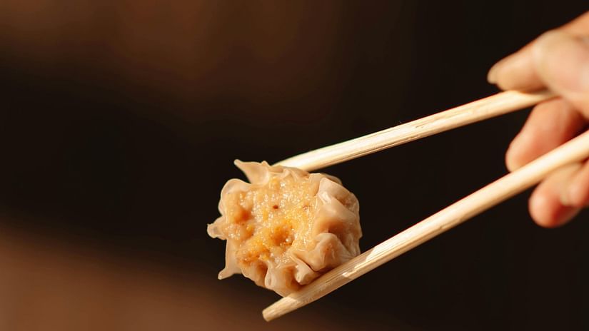 A close-up of a dumpling held by a chopstick.